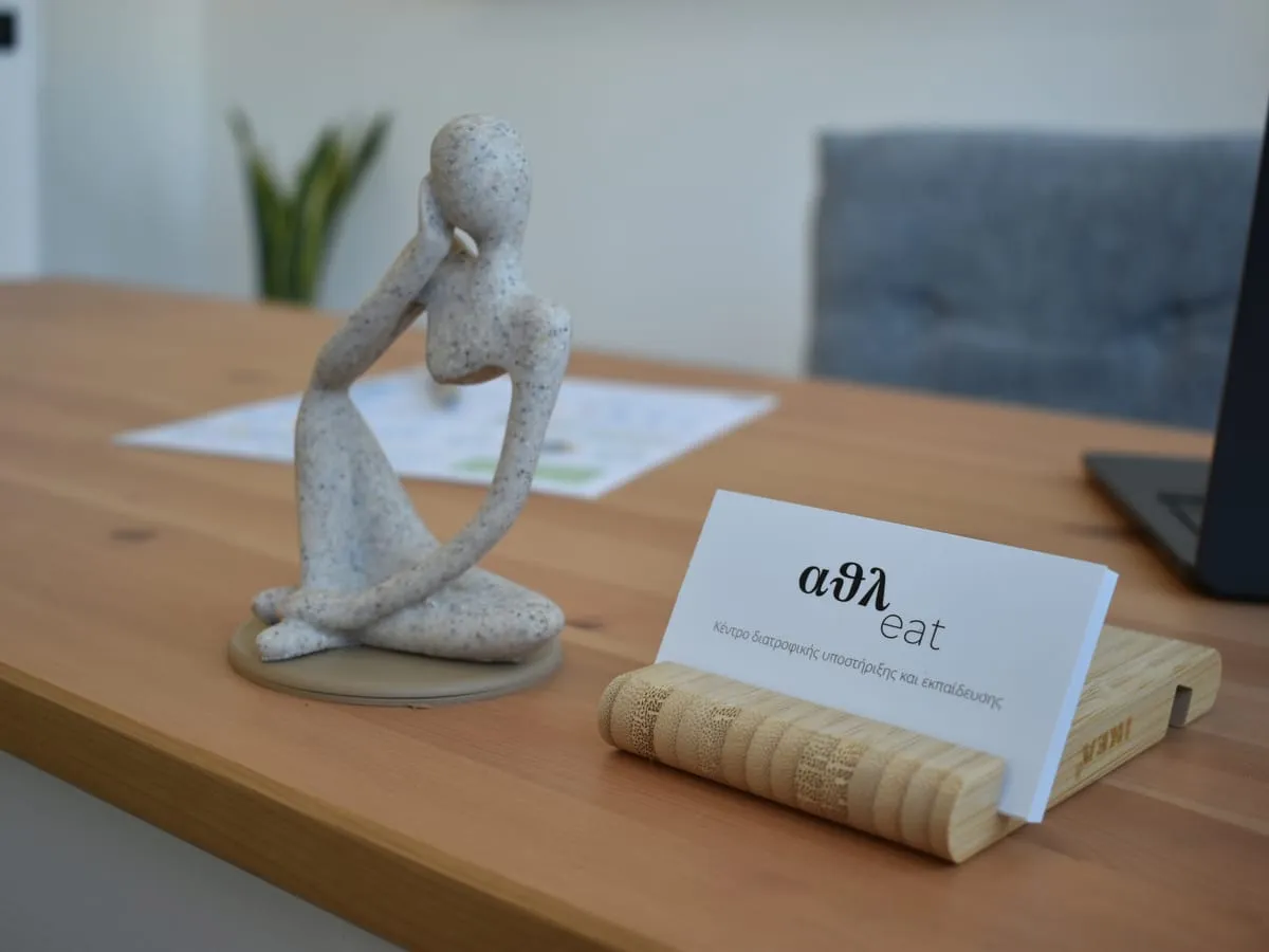 The athleat office in Peristeri: the branded card on the wooden desk, next to a decorative sculpture.